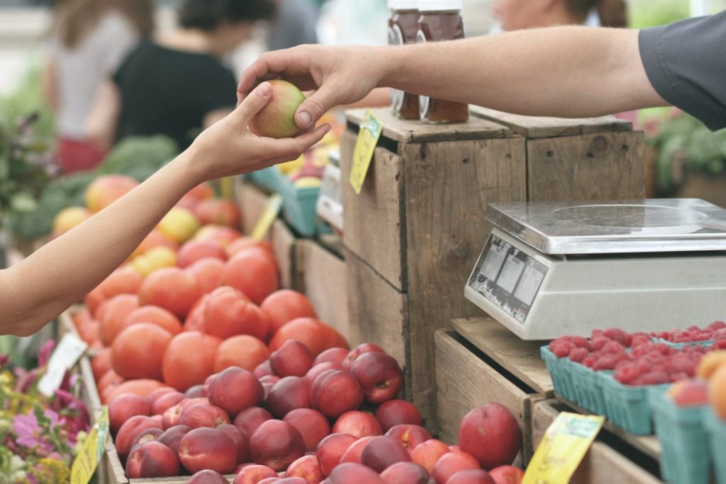 handing off an apple at the farmers market