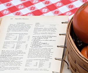 Cookbook of tomato recipes next to a basket of my fresh garden tomatoes.