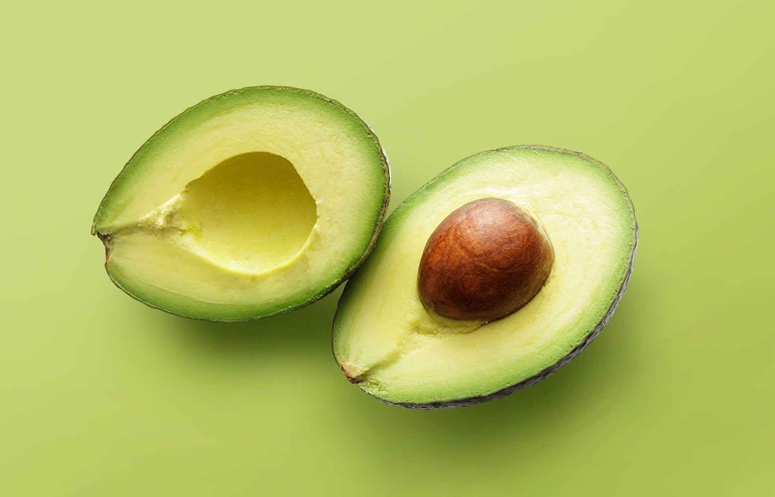 avocado cut in half on green background